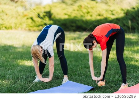 Women stretching on mats in a park 136556299