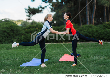 Two people exercise together in the park Two people exercise together in the park 136556325