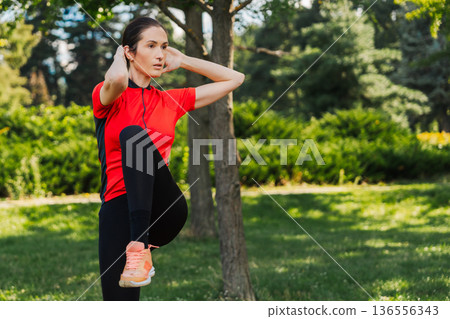 Woman exercises in park during sunny day Woman exercises in park during sunny day 136556343
