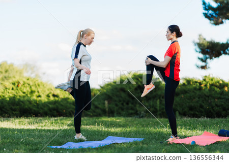 Two women work out in a park at dusk Two women work out in a park at dusk 136556344