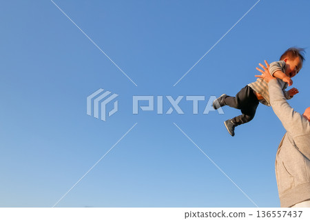 天空下,笑容燦爛的孩子被高高舉起。 天空下,笑容燦爛的孩子被高高舉起。 136557437