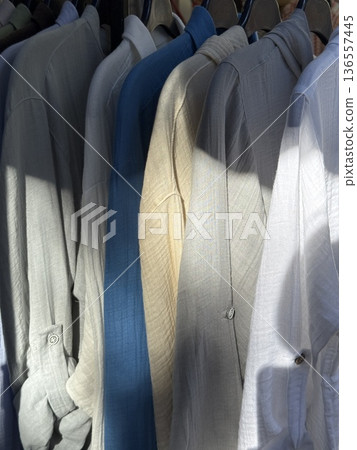 Stack of neatly folded shirts in varying colors under soft sunlight, suitable for background 136557445