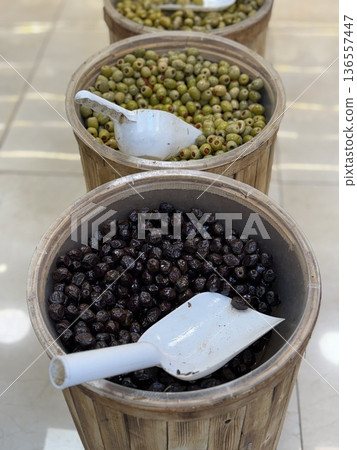 Olives in wooden barrels with scoops, showcasing different varieties at a market Olives in wooden barrels with scoops, showcasing different varieties at a market 136557447