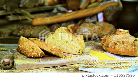 Fresh bread is displayed on a wooden table in a market setting during the day with various types and textures Fresh bread is displayed on a wooden table in a market setting during the day with various types and textures 136557580