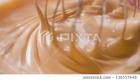 Mixing cream in a bowl with a whisk during a kitchen activity in the morning light 136557648