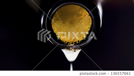 Beer pours slowly from a bottle onto a dark surface during a casual evening gathering Beer pours slowly from a bottle onto a dark surface during a casual evening gathering 136557661