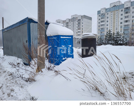 On a winter day, a mobile blue plastic toilet stall outside. 136557700