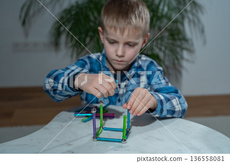 Child engaged in hands-on learning activity at home using a colorful magnetic construction set. Homeschooling concept, cognitive growth, creative exploration and screen-free educational play Child engaged in hands-on learning activity at home using a colorful magnetic construction set. Homeschooling concept, cognitive growth, creative exploration and screen-free educational play 136558081