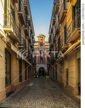 Narrow European Street Leading to Historic Church Facade Between Sunny Apartment Balconies 136558213