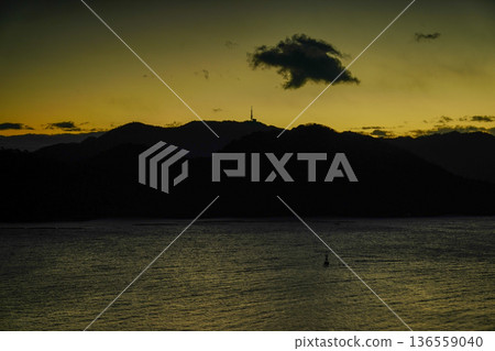 Twilight sea, mountain silhouette, golden sky, calm water surface, lonely cloud 136559040