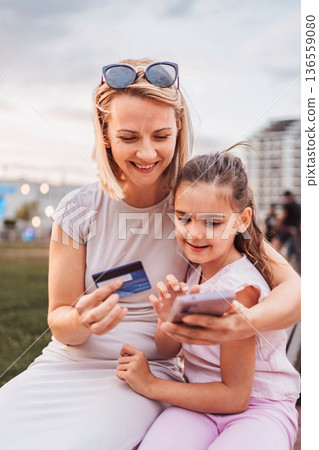 Mother and daughter shopping online using a credit card and a smartphone 136559080