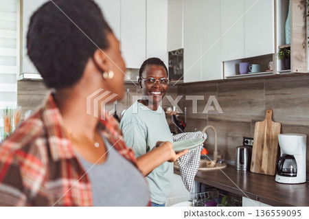 Two roommates sharing housework, drying dishes in the kitchen Two roommates sharing housework, drying dishes in the kitchen 136559095