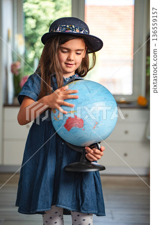 Little girl holding a globe and learning geography at home 136559157