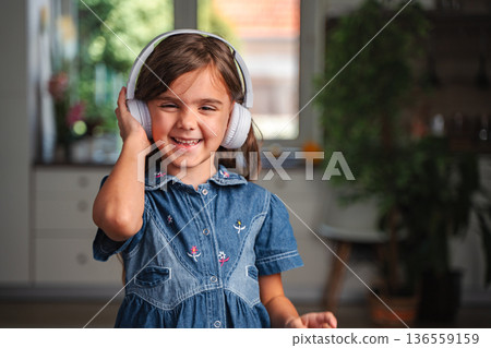 Smiling student girl enjoying music with headphones at home 136559159