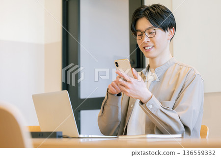 一位戴眼鏡的男子在咖啡館使用智慧型手機。 一位戴眼鏡的男子在咖啡館使用智慧型手機。 136559332
