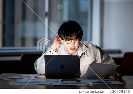 A man in work clothes working overtime 136559390