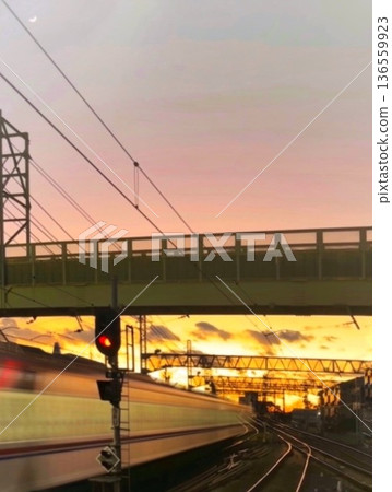 A crescent moon and the light trail of a train running down a railway at dusk A crescent moon and the light trail of a train running down a railway at dusk 136559923