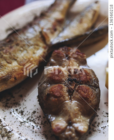 Montenegrin cuisine, fish assortment platter, fried grilled crucian carp steak, roasted pastrmka and bleak on plate with lemon and salad served in a restaurant in Montenegro, Skadar lake, Virpazar 136560218