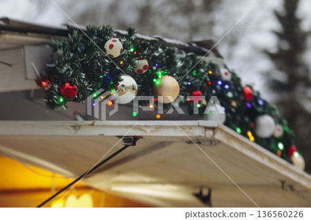 Christmas market with illuminated food stalls, gift shops and kiosks, New Year outdoor fair decorations, garlands and festoons, Xmas atmosphere, retail and store illumination, decor in Europe city Christmas market with illuminated food stalls, gift shops and kiosks, New Year outdoor fair decorations, garlands and festoons, Xmas atmosphere, retail and store illumination, decor in Europe city 136560226