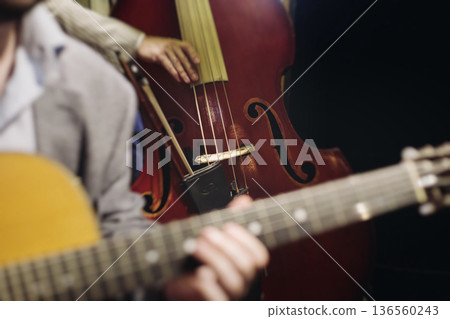 Concert view of contrabass violoncello player with vocalist and musical band during string concert, jazz orchestra performing music, violoncellist cello jazz player on stage in club, music arena hall 136560243