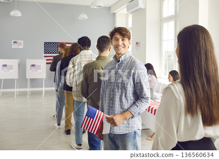 Happy young male American voter with flag of USA standing in line at polling station Happy young male American voter with flag of USA standing in line at polling station 136560634