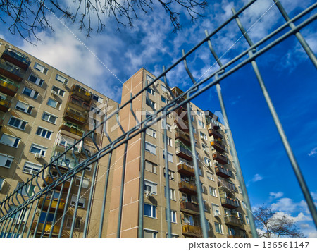 Budapest Kassai utca Apartment Building Architecture with Blue Metal Fence Foreground under Bright Sunny Sky Socialist Era Housing Block Residential District View Hungary Urban Landscape Budapest Kassai utca Apartment Building Architecture with Blue Metal Fence Foreground under Bright Sunny Sky Socialist Era Housing Block Residential District View Hungary Urban Landscape 136561147