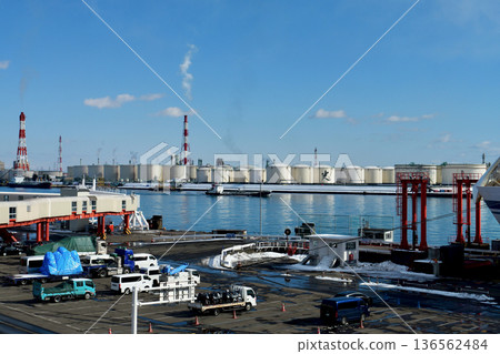 A cargo ship sails through the bay with the Tomakomai West Port industrial complex in the background on a clear winter day 136562484