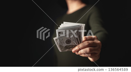 Hand offering banknote forward symbolizing cash payment, money exchange 136564589