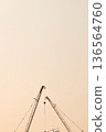 A tall construction crane and an orange sky background. 136564760