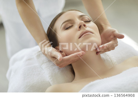 Massage and facial skin treatment for woman by therapist hands touching chin Massage and facial skin treatment for woman by therapist hands touching chin 136564908