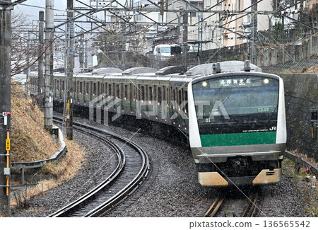E233 series train running through falling snow 136565542