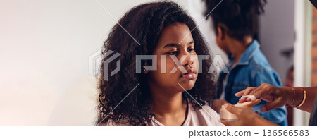 Stylist is putting make up on black woman eyebrows with the eyebrows brush. 136566583