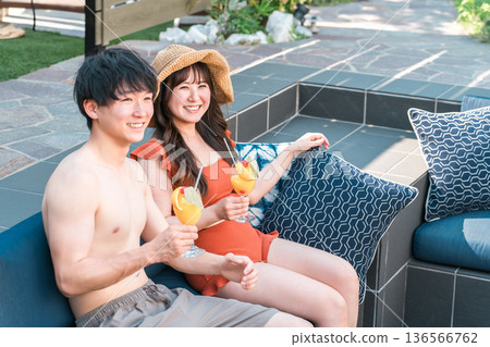 Asian couple in swimwear relaxing in a jacuzzi by the pool Asian couple in swimwear relaxing in a jacuzzi by the pool 136566762