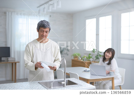 A couple in their 60s having a conversation while washing dishes in the kitchen A couple in their 60s having a conversation while washing dishes in the kitchen 136566859