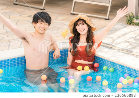 Young Asian couple playing in the pool on a resort vacation Young Asian couple playing in the pool on a resort vacation 136566898