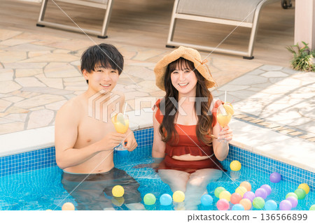 A couple in swimsuits playing in the pool at a resort hotel on a trip, back view of a married couple 136566899
