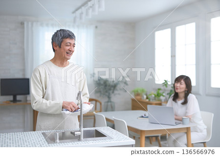 A couple in their 60s having a conversation while washing dishes in the kitchen A couple in their 60s having a conversation while washing dishes in the kitchen 136566976