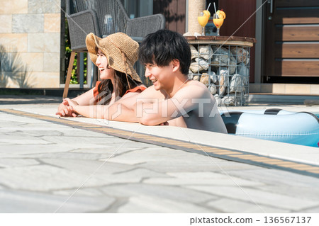 Young Asian couple playing in the pool on a resort vacation Young Asian couple playing in the pool on a resort vacation 136567137