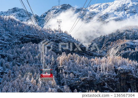 Matterhorn Glacier Paradise red cable car ride over snow-covered alpine forests and mountains. 136567304