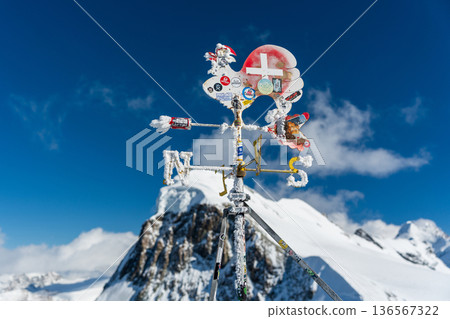Rooster-shaped weather vane on a mountaintop covered in frost and covered with stickers, Zermatt, Valais, Switzerland 136567322
