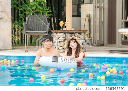 Young Asian couple playing with swim rings in the pool (vacation, resort, vacation, overseas travel) Young Asian couple playing with swim rings in the pool (vacation, resort, vacation, overseas travel) 136567391