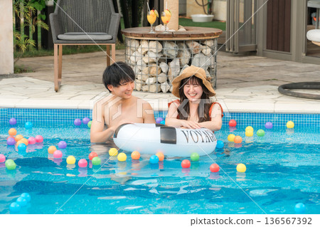 Young Asian couple playing with swim rings in the pool (vacation, resort, vacation, overseas travel) Young Asian couple playing with swim rings in the pool (vacation, resort, vacation, overseas travel) 136567392