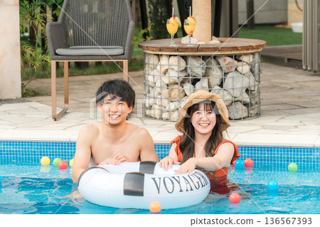 Young Asian couple playing with swim rings in the pool (vacation, resort, vacation, overseas travel) Young Asian couple playing with swim rings in the pool (vacation, resort, vacation, overseas travel) 136567393