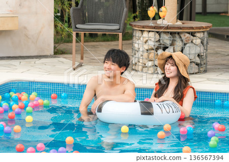 Young Asian couple playing with swim rings in the pool (vacation, resort, vacation, overseas travel) Young Asian couple playing with swim rings in the pool (vacation, resort, vacation, overseas travel) 136567394
