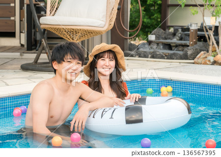 一對年輕的亞洲夫婦在泳池裡玩游泳圈（度假，度假村，出國旅行） 136567395
