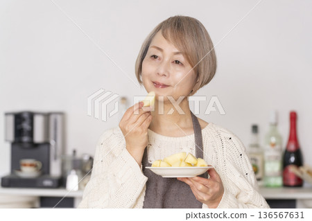 Senior woman peeling an apple in the kitchen Senior woman peeling an apple in the kitchen 136567631