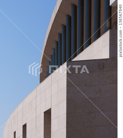 Low-angle composition of the exterior of a modern building and circular columns against the blue sky 136567840