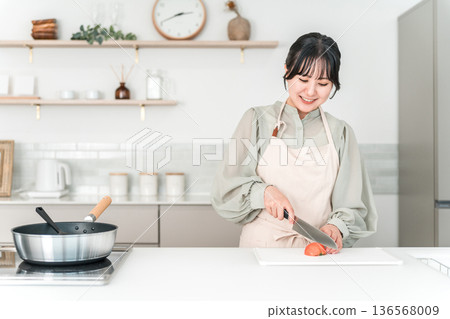 年輕的亞裔女子穿著圍裙在廚房做飯 136568009