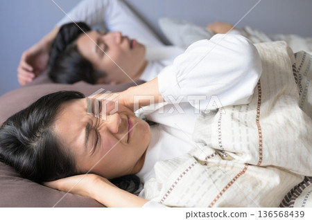 一位女士因伴侶的鼾聲而煩惱 一位女士因伴侶的鼾聲而煩惱 136568439
