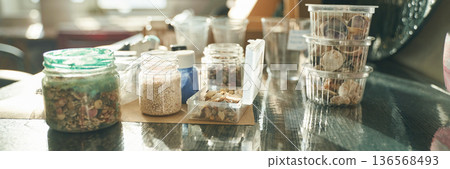 Various herbs and spices in jars and containers on a sunlit kitchen table 136568493